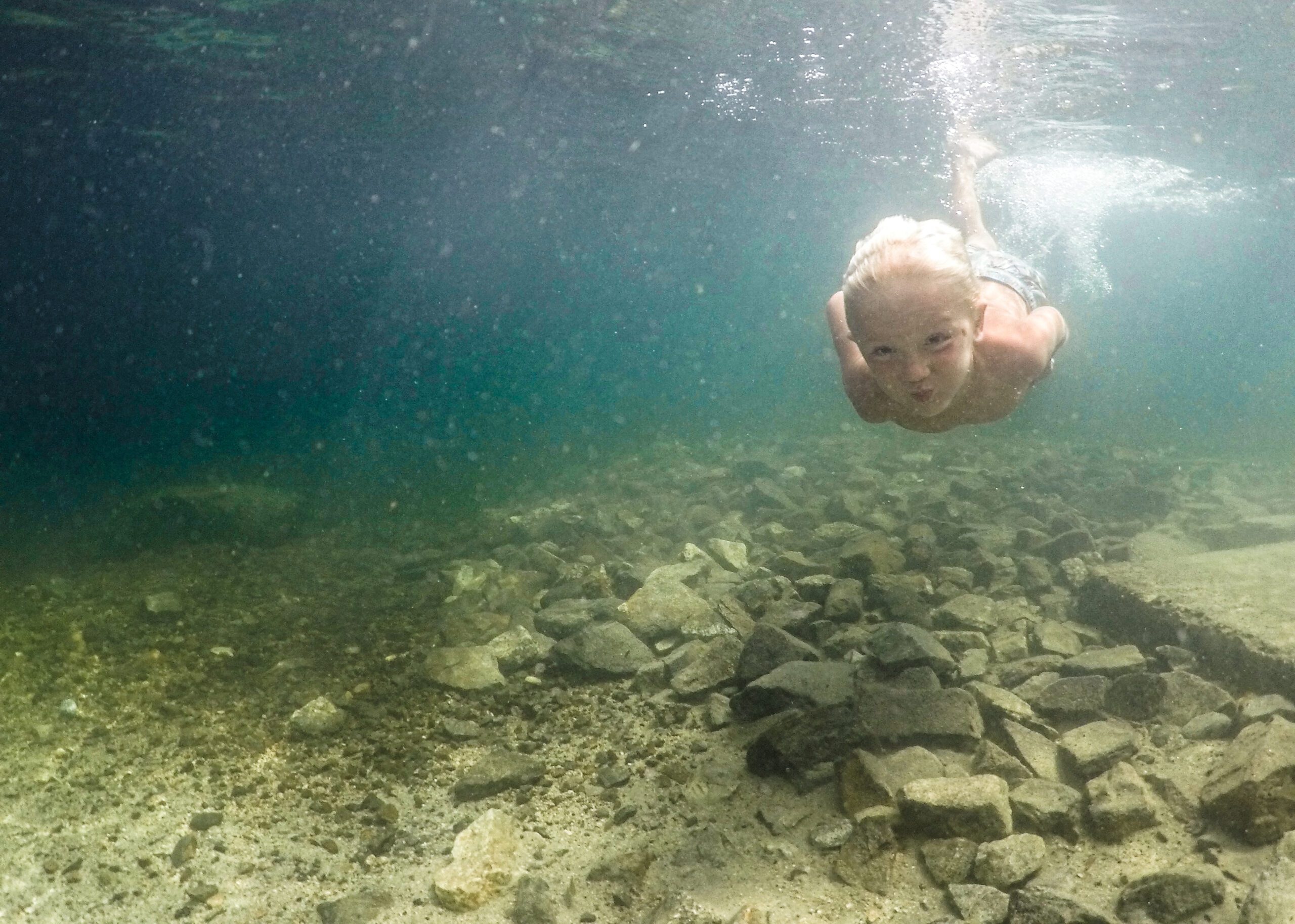 Photography vacation photos and video session with child swimming at the bottom of a lake in Idaho